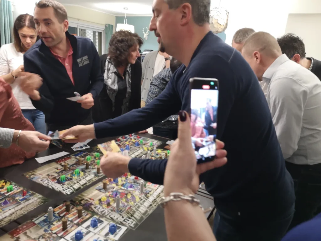Deux participants échangent des cartes et des billets au-dessus du plateau