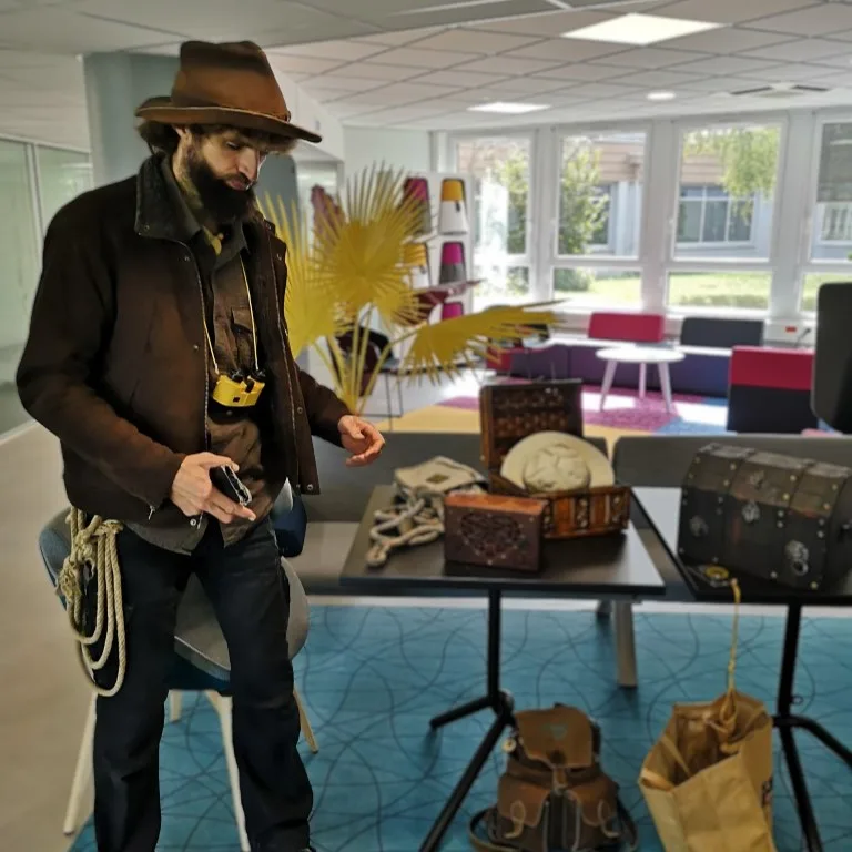 Un animateur en tenue d’explorateur, devant des coffres posés sur une table de bureau