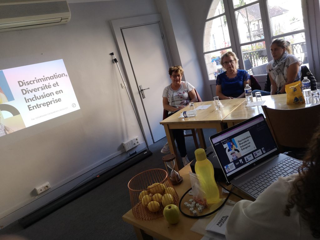 Atelier 10Torsions sur la discrimination, la diversité et l’inclusion en entreprise, participantes autour d’une table devant la diapositive du même titre