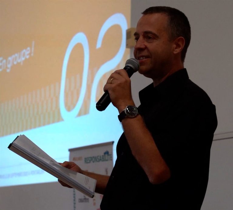 Olivier Bourgeois, micro en main et notes à la main, anime une formation devant un écran de projection.
