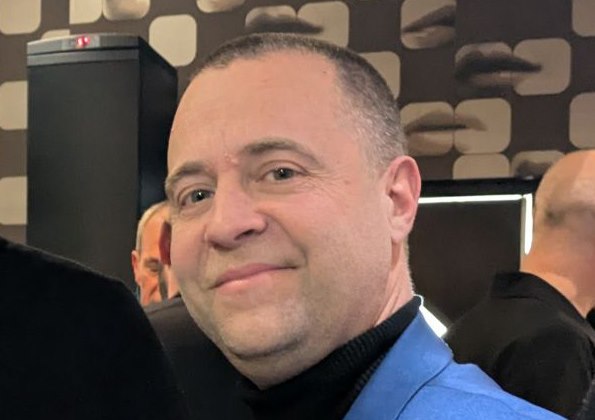 Un membre de l’équipe 10Torsions en veste bleue, badge 10Torsions au revers, pendant une soirée